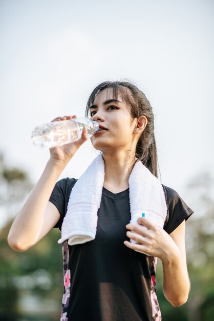 Women stand to drink water after exercise