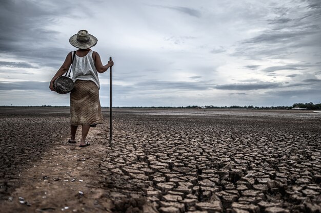 乾燥した土壌と漁具の上に立っている女性、地球温暖化と水危機