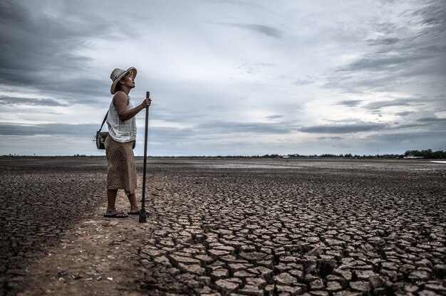 Women standing on dry soil and fishing gear, global warming and water crisis