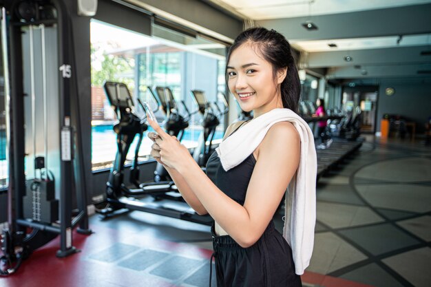 Women standing playing the phone happily in the gym.