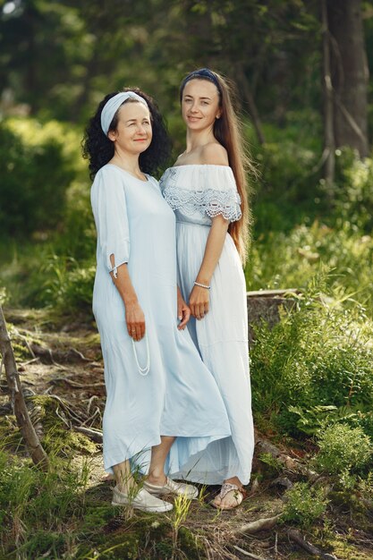 Women in a summer forest. Lady in a blue dress. Family posing and embracing.