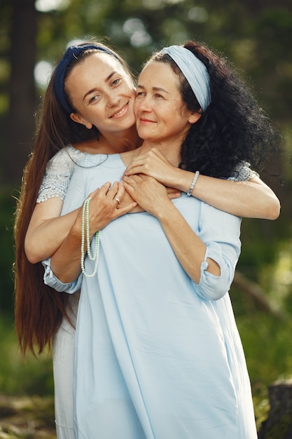 Women in a summer forest. Lady in a blue dress. Family posing and embracing.