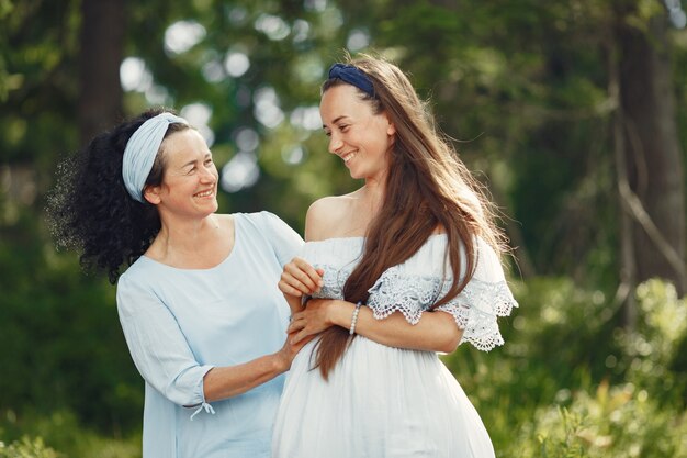 Women in a summer forest. Lady in a blue dress. Family posing and embracing.