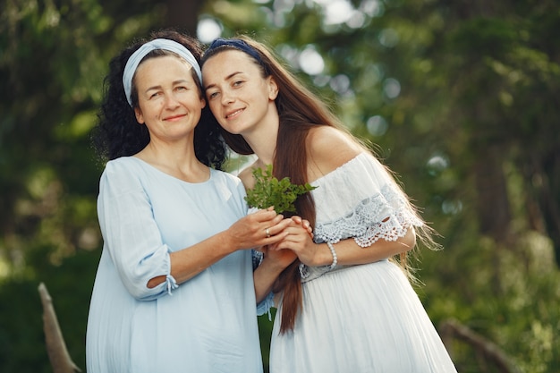 Free photo women in a summer forest. lady in a blue dress. family posing and embracing.