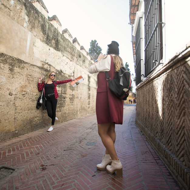 Women taking pictures on narrow street