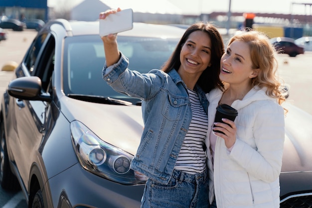 Free photo women taking a selfie next to a car