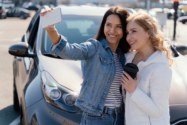 Women taking a selfie next to a car