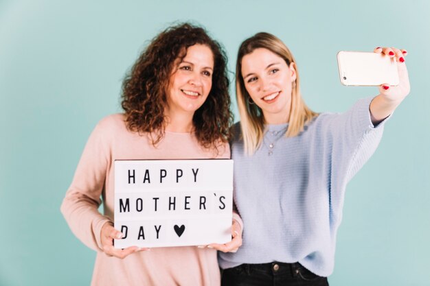 Women taking selfie with Mother's Day greeting