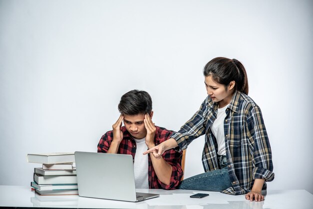 Women teach men how to work with laptops at work.