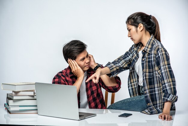 Women teach men how to work with laptops at work.