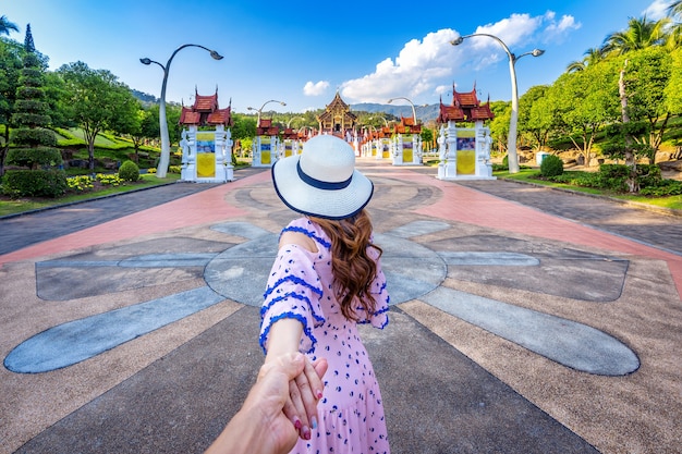 Women tourists holding man's hand and leading him to Ho kham luang northern thai style in Royal Flora ratchaphruek in Chiang Mai,Thailand.