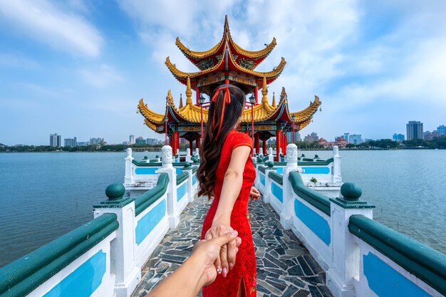 남자의 손을 잡고 그를 대만의 가오슝의 유명한 관광 명소로 인도하는 여성 관광객.