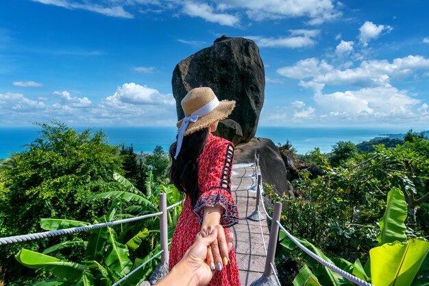 Women tourists holding mans hand and leading him to overlap stone at Koh Samui Thailand