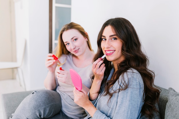 Women using cosmetics on couch