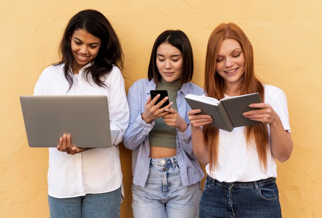 Women using different objects in front of a yellow wall