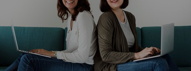 Women using laptop on sofa together