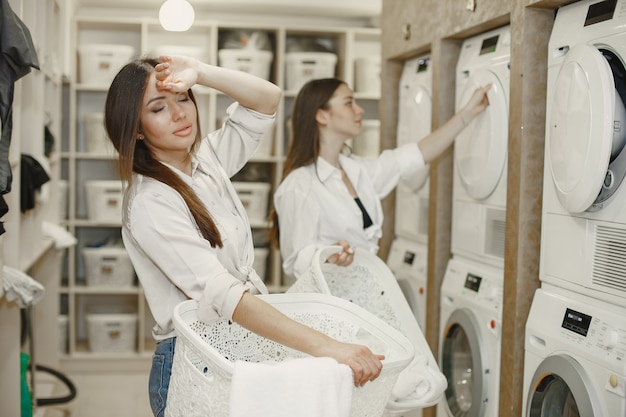 Women using washing machine doing the laundry. Young girls ready to wash clothes. Interior, washing process concept