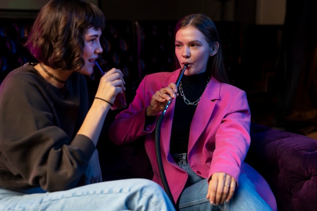 Free photo women vaping from a hookah indoors