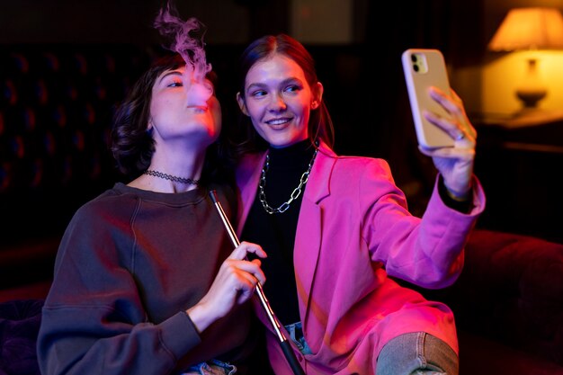 Women vaping from a hookah indoors