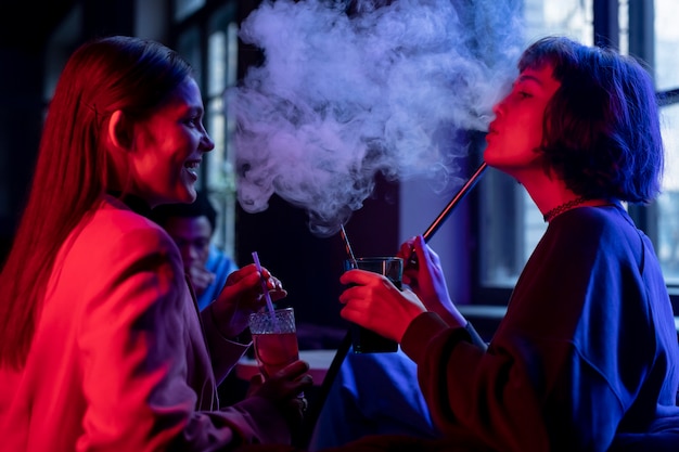 Women vaping from a hookah indoors