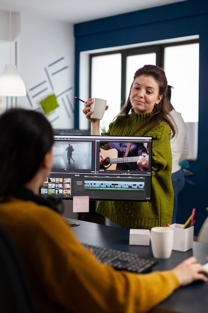 Женщины-видеооператоры редактируют видеопроект, создают контент, команда блоггеров сидит в современной студии start-up office