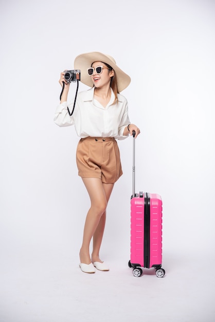 Women wear hats, glasses, luggage, and carry cameras on the way to travel