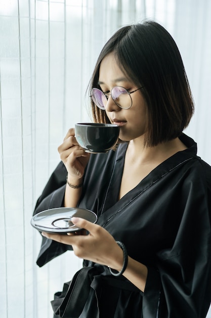 Women wearing black robes, handing coffee in the bedroom.