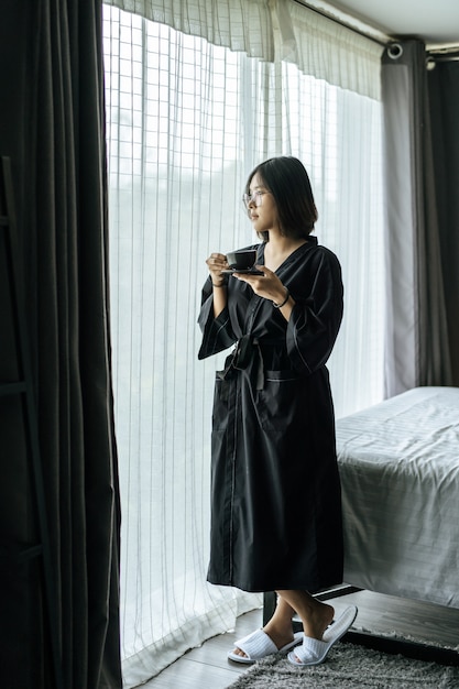 Free photo women wearing black robes, handing coffee in the bedroom.