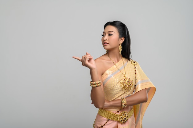 상징적이며 손가락을 가리키는 태국 의상을 입은 여성