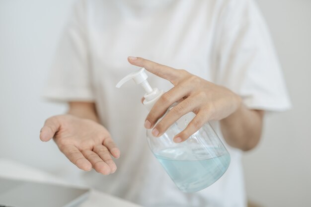 ジェルを押して手を洗う白いシャツを着ている女性。