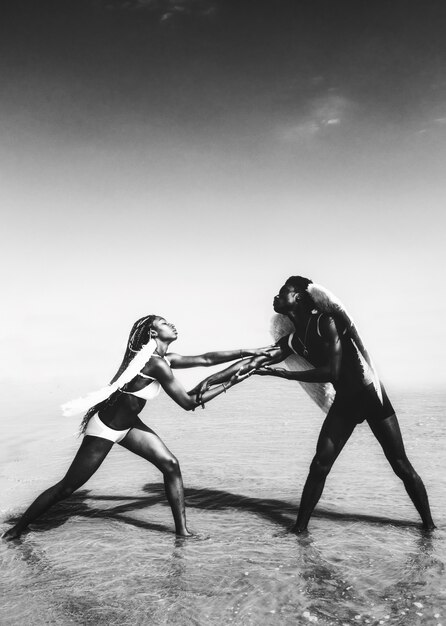 Women in white and black bikini and wings on beach