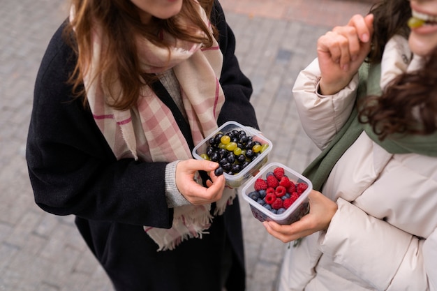 Free photo women with berries outdoors high angle