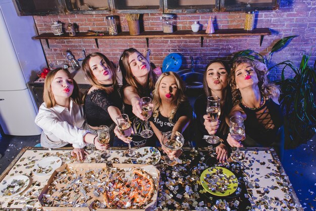 women with champagne sending air kiss