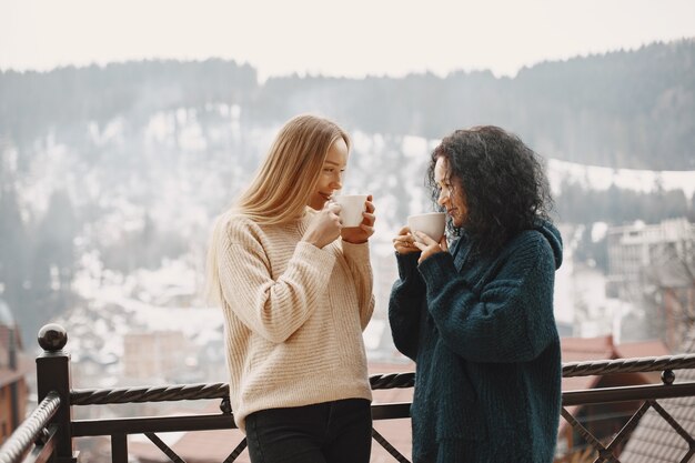 一杯のコーヒーを持つ女性。山での素晴らしい休日。雪の降る天気。