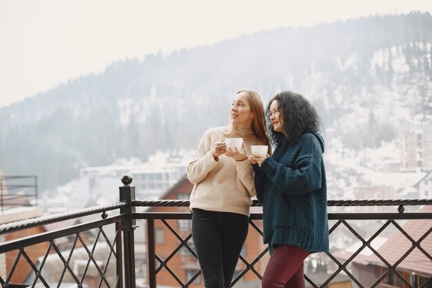 Women with a cup of coffee. Wonderful holiday in mountains. Snowy weather.