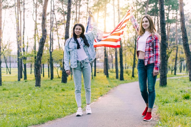 屋外を歩くアメリカの国旗を持つ女性