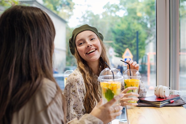 カフェで話している新鮮な飲み物を持つ女性