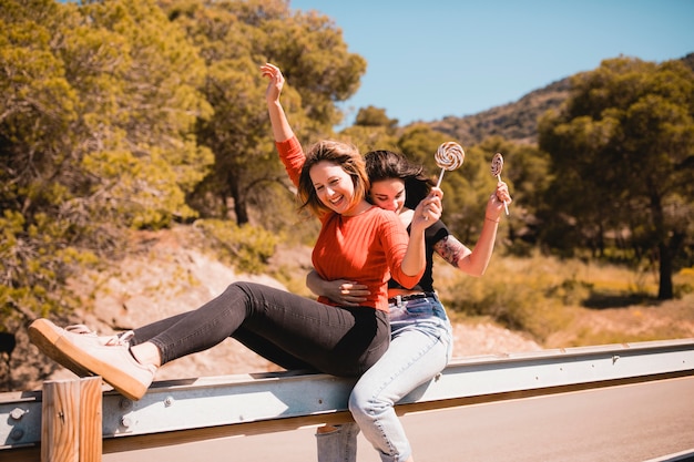 Free photo women with lollipops sitting on guard rail