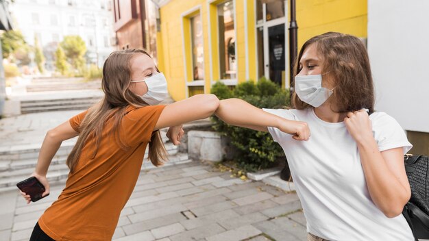 Women with medical masks practicing elbow salute