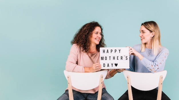 Women with Mother's Day greeting on chairs