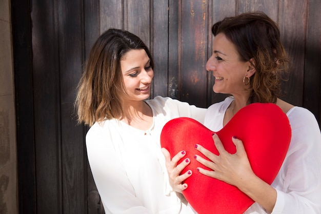 Foto gratuita donne con cuore peluche vicino alla porta di legno