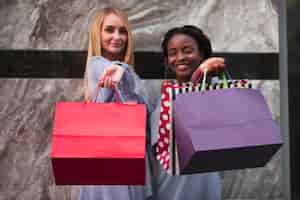 Free photo women with shopping bags looking at camera