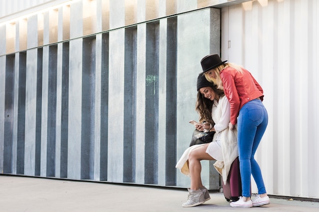 Women with suitcase using smartphone