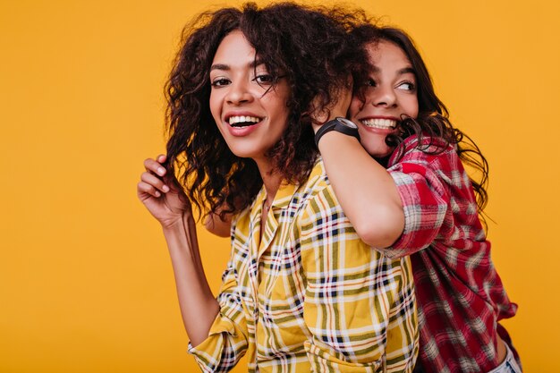 women with tanned skin are fooling around. pretty girl tousling her friend's hair.