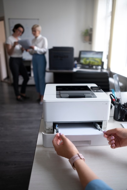 Foto gratuita donne al lavoro in ufficio utilizzando la stampante