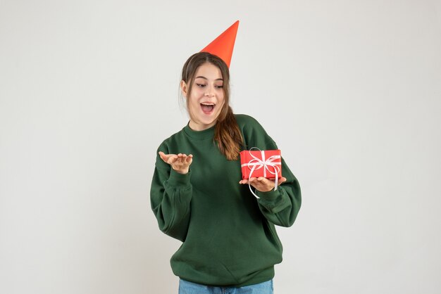 wondered girl with party cap holding her xmas gift on white