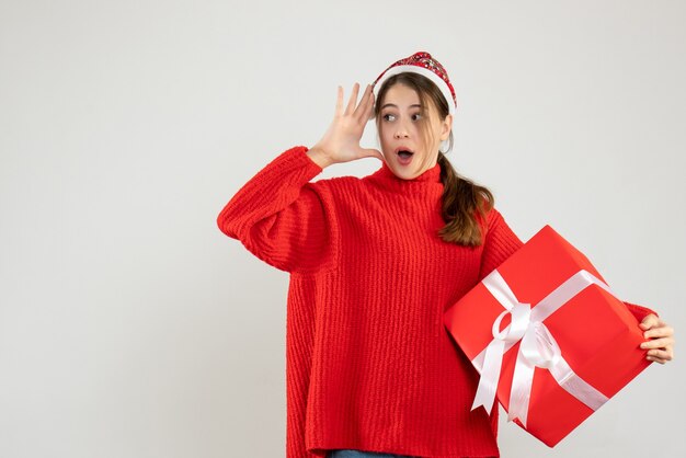 wondered girl with santa hat holding gift on white