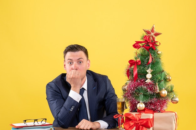 удивился человек, сидящий за столом возле рождественской елки и подарков на желтом