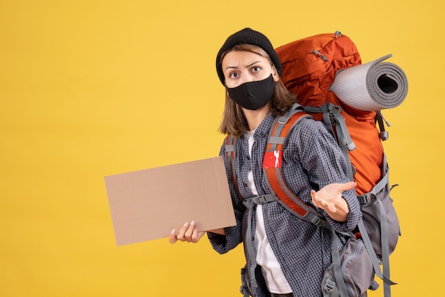 wondered traveler girl with black mask and backpack holding cardboard