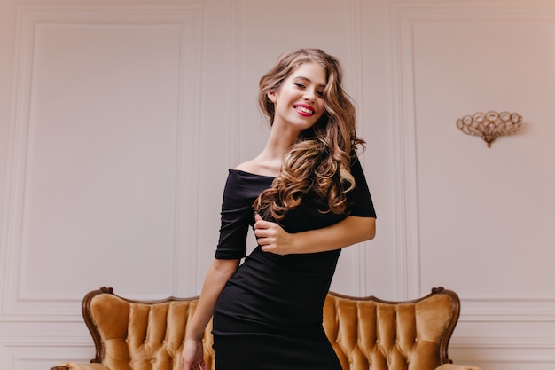 Wonderful, cute Slavic model woman with dazzling smile defiantly poses for portrait against white wall